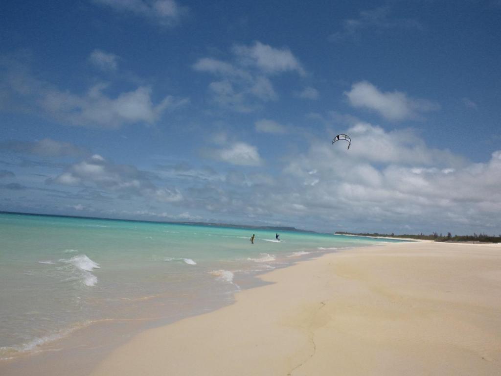a person is flying a kite on a beach at Guest House Miyakojima in Miyako-jima