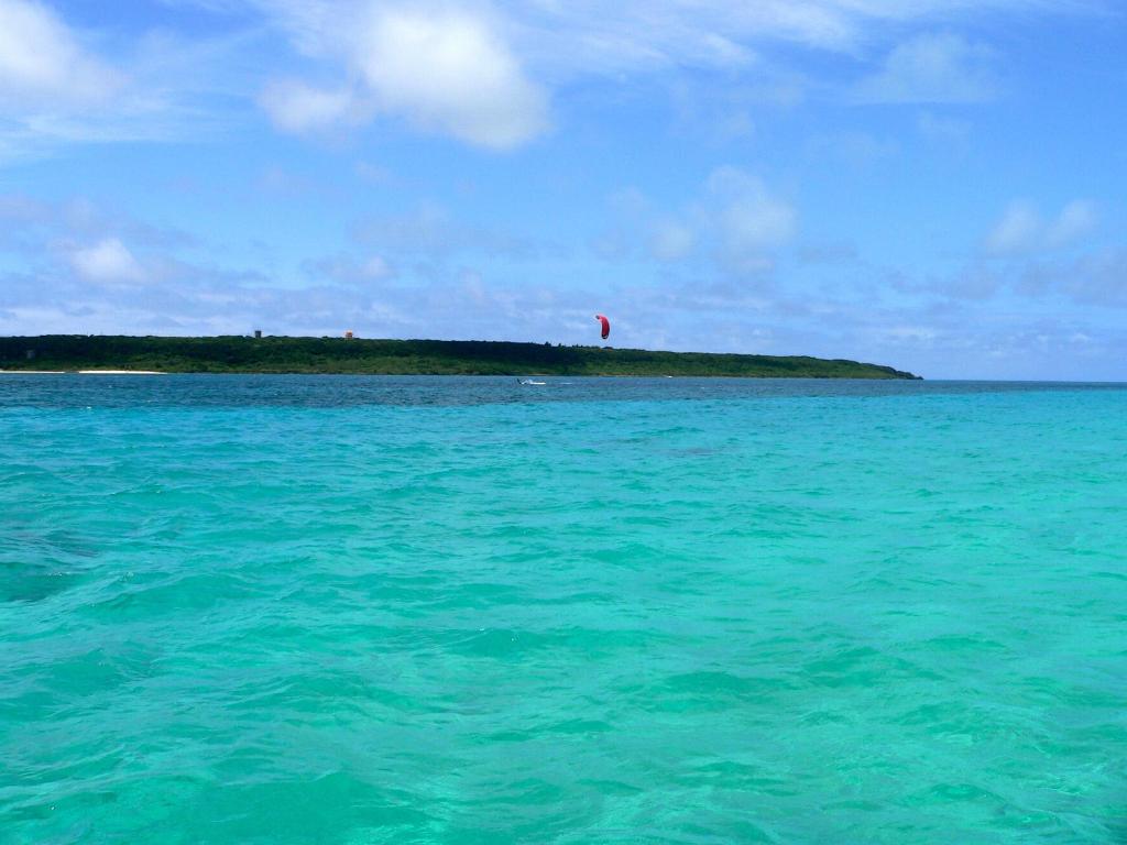an island in the ocean with a kite in the sky at Guest House Miyakojima in Miyako-jima