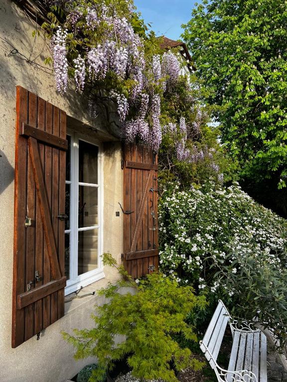 une maison avec une porte en bois, un banc et des fleurs dans l'établissement Un secret bien gardé, à Fontenay-le-Fleury