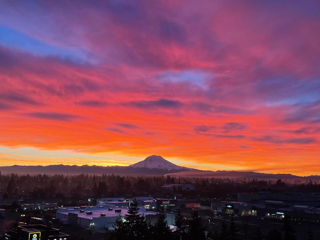een zonsondergang boven een stad met een berg op de achtergrond bij Double room-wake up to stunning sunrises, unwind magical sunsets in Tacoma