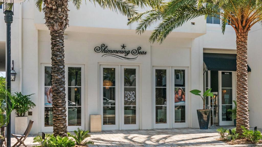 a white building with palm trees in front of it at Lazy Days in Seacrest