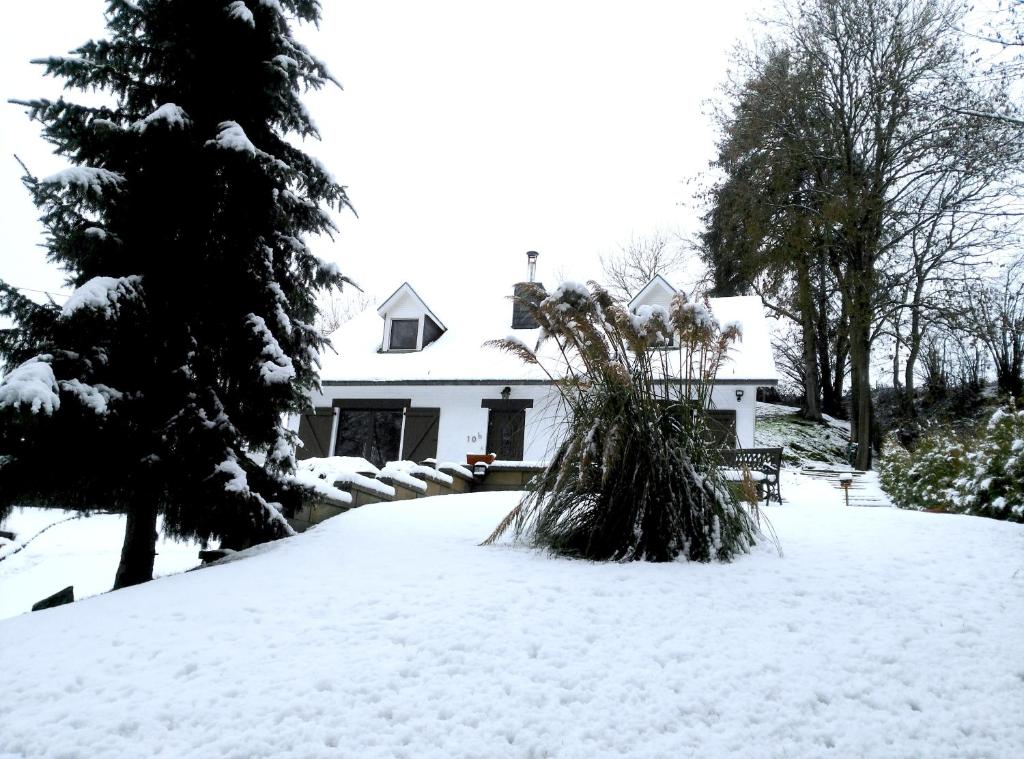 a snow covered yard with a white house at WesterOurthe 2 personen Sauna in Durbuy
