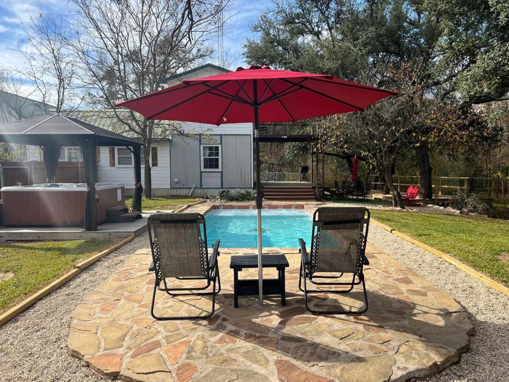two chairs and a table with an umbrella next to a pool at Farmhouse, Private Pool, Spa and Gym! Waco 30 min in Gatesville