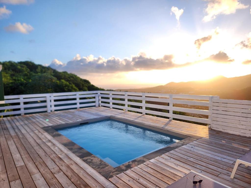 einen Whirlpool auf einer Holzterrasse mit einem Zaun in der Unterkunft Villa with pool and panoramic view in Rivière-Pilote