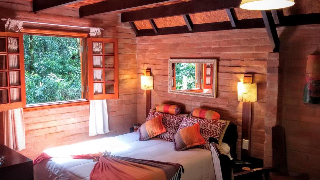 a bedroom with a bed in a room with two windows at Ecos da Terra Chalés in Monte Verde