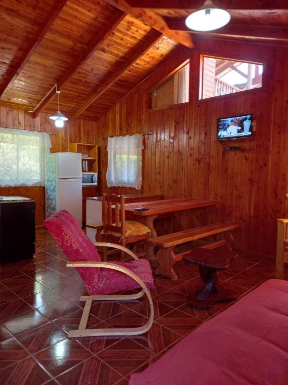 a living room with a table and chairs and a kitchen at Lican Ray Cabañas Los Primos in Licán Ray
