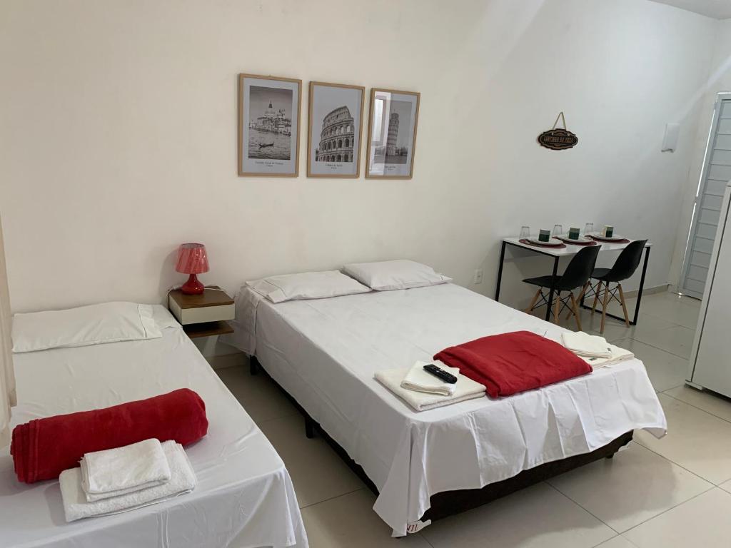 a bedroom with two beds and a table with chairs at Loft ROMA para Casais, em Iguaba Grande, 3 Pessoas, 150 metros da praia in Iguaba Grande