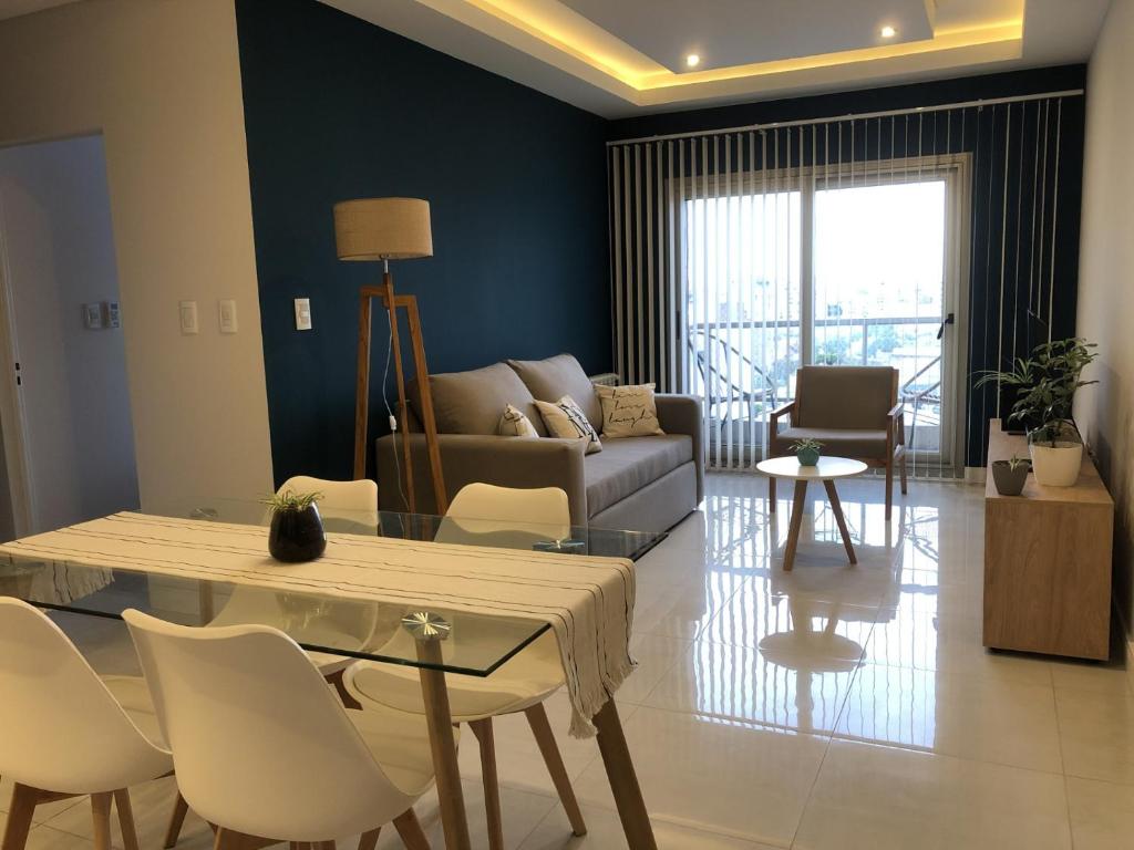 Una sala de estar con un sofá, una mesa y sillas. en Departamento MARTINIANO con cochera, en Bahía Blanca