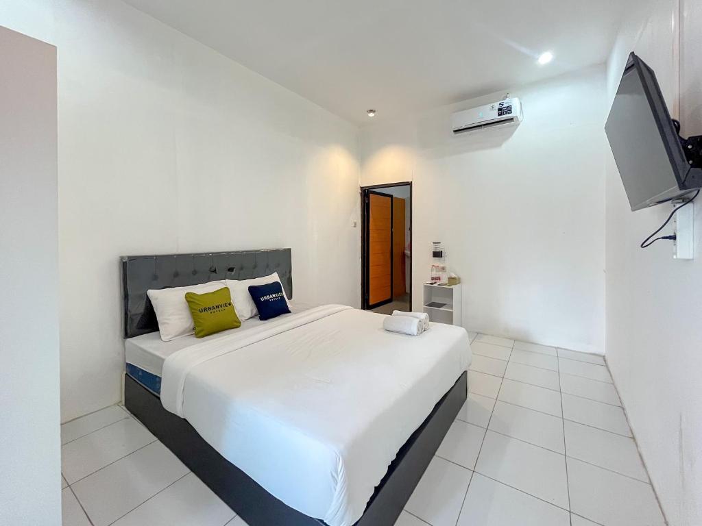 a white bedroom with a bed and a flat screen tv at Urbanview Trunojoyo Homestay Banyuwangi by RedDoorz in Banyuwangi