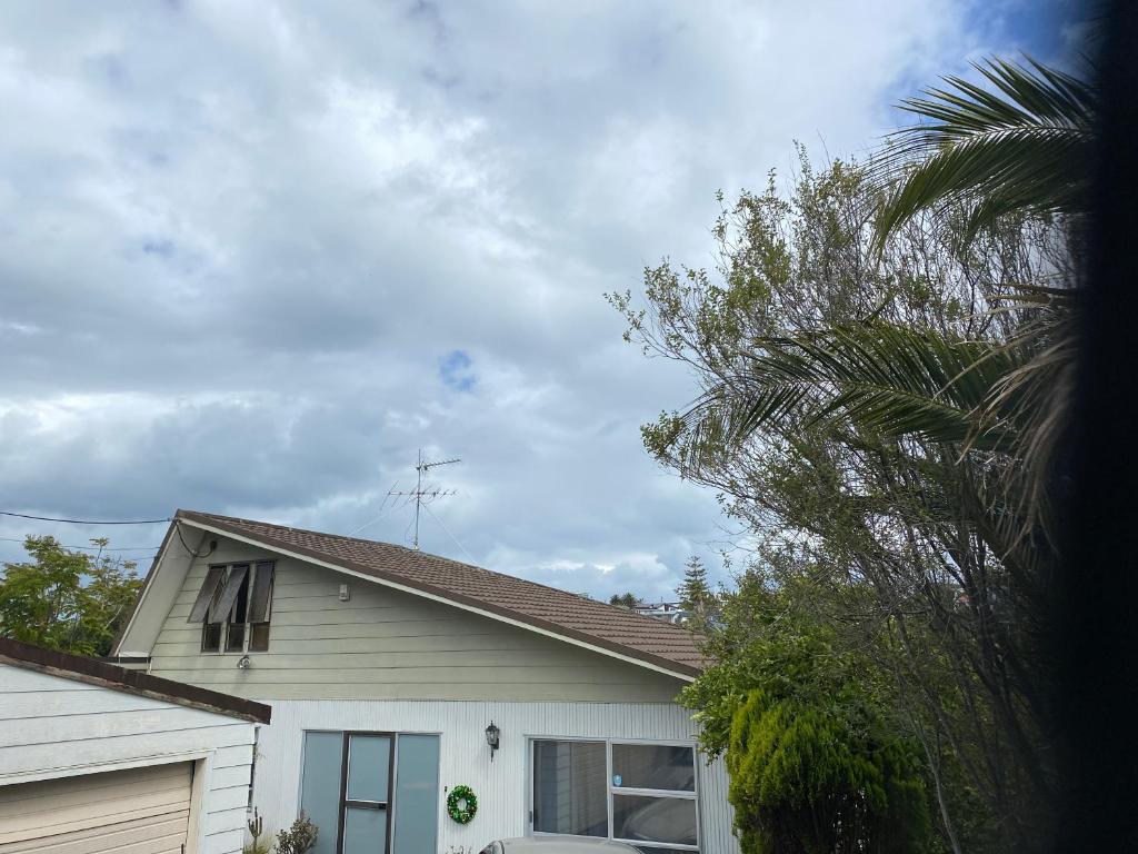 una casa blanca con una palmera delante en Bays stay, en Auckland