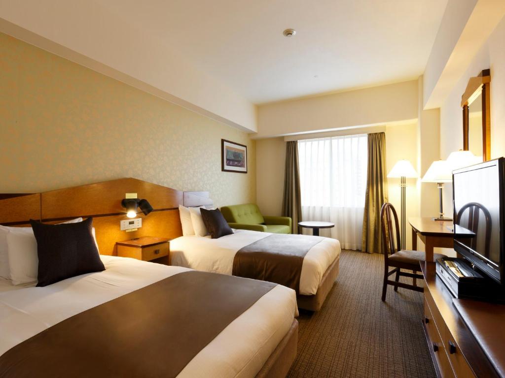 una camera d'albergo con due letti e una televisione di Hotel Resol Gifu a Gifu
