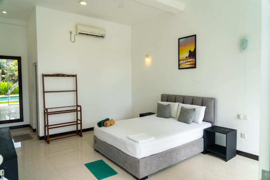 a bedroom with a large white bed and a window at Green Hill Mirissa in Mirissa