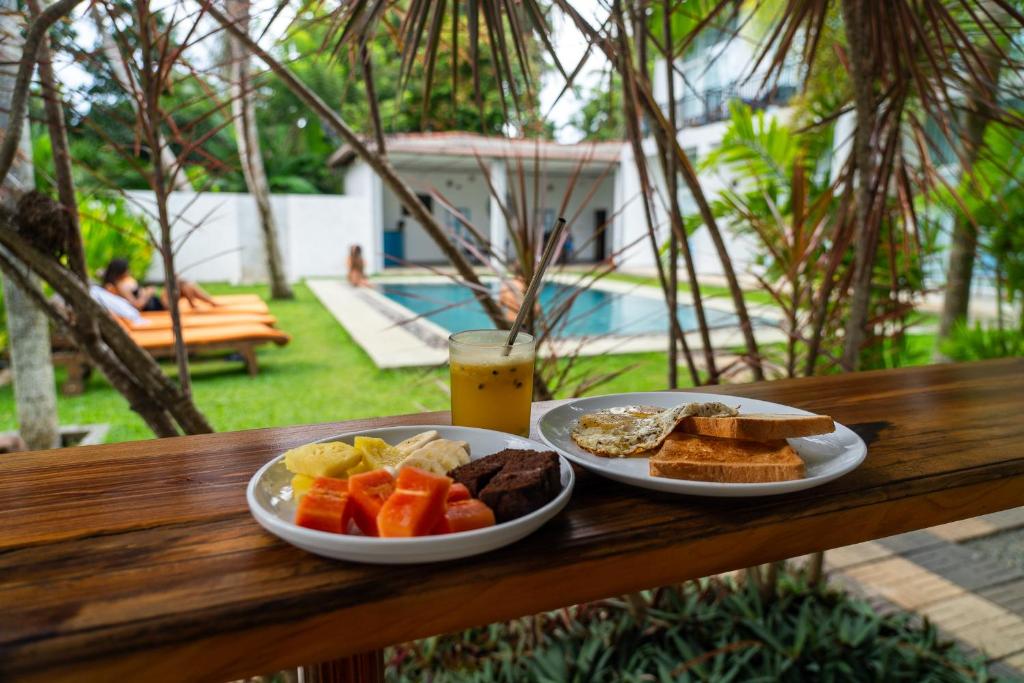 a breakfast of bread and toast and a drink on a wooden table at Green Hill Mirissa in Mirissa