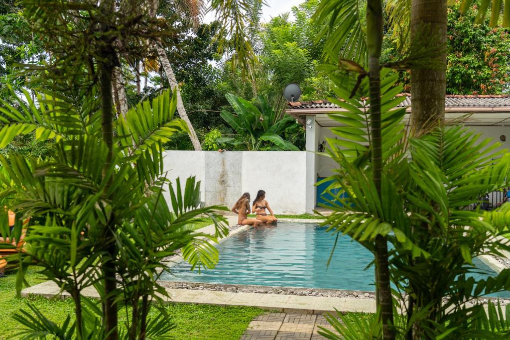two women sitting in a swimming pool in a backyard at Green Hill Mirissa in Mirissa