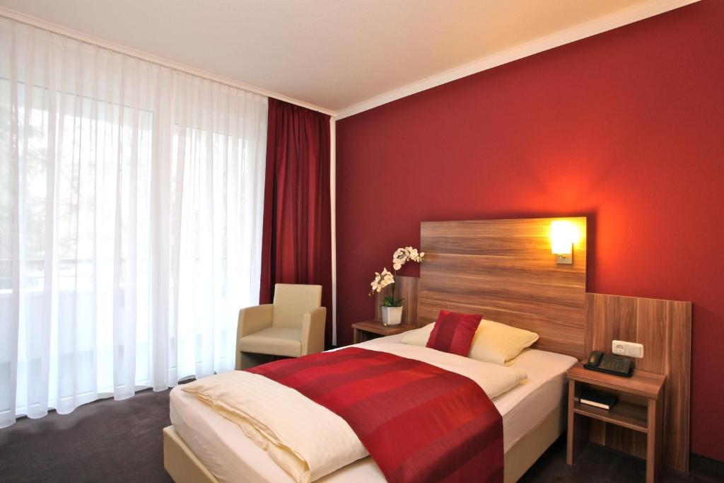 um quarto com uma cama com uma parede vermelha em Waldhotel Bad Soden em Bad Soden am Taunus