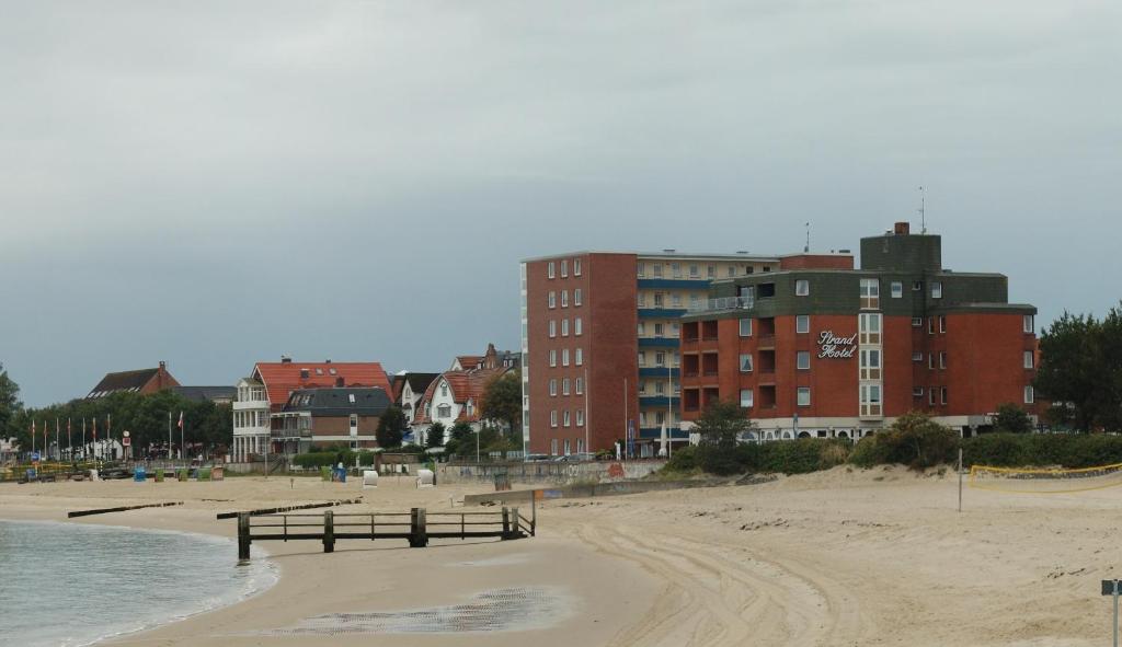 Blick auf einen Strand mit Gebäuden im Hintergrund in der Unterkunft Strandhotel in Wyk auf Föhr