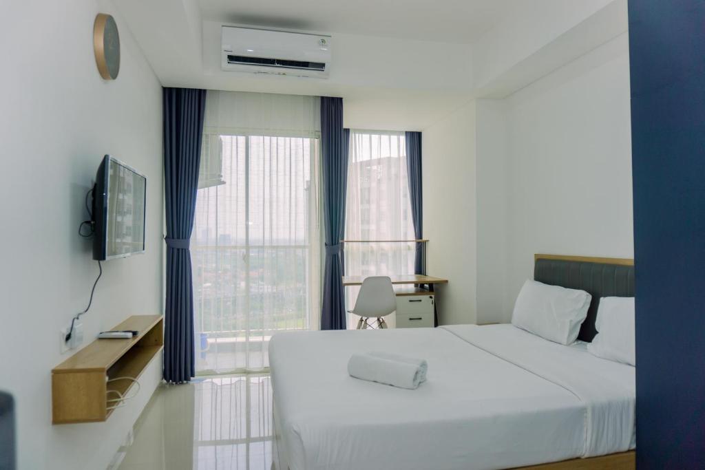 a bedroom with a white bed and a window at Good Deal and Homey Studio Pacific Garden Apartment By Travelio in Tangerang