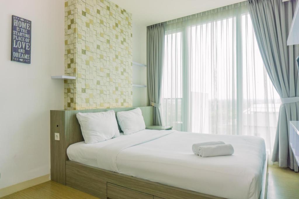 a bed in a room with a large window at Cozy Living Studio Apartment Tree Park City BSD By Travelio in Tangerang