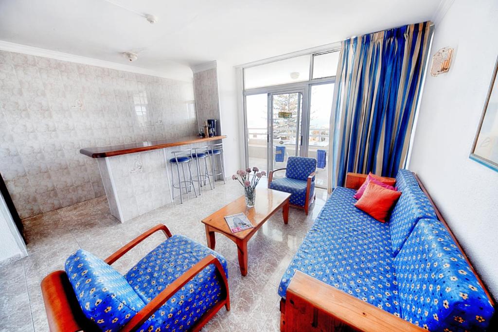 a living room with a blue couch and two chairs at Apartamentos Montemar in Playa del Ingles
