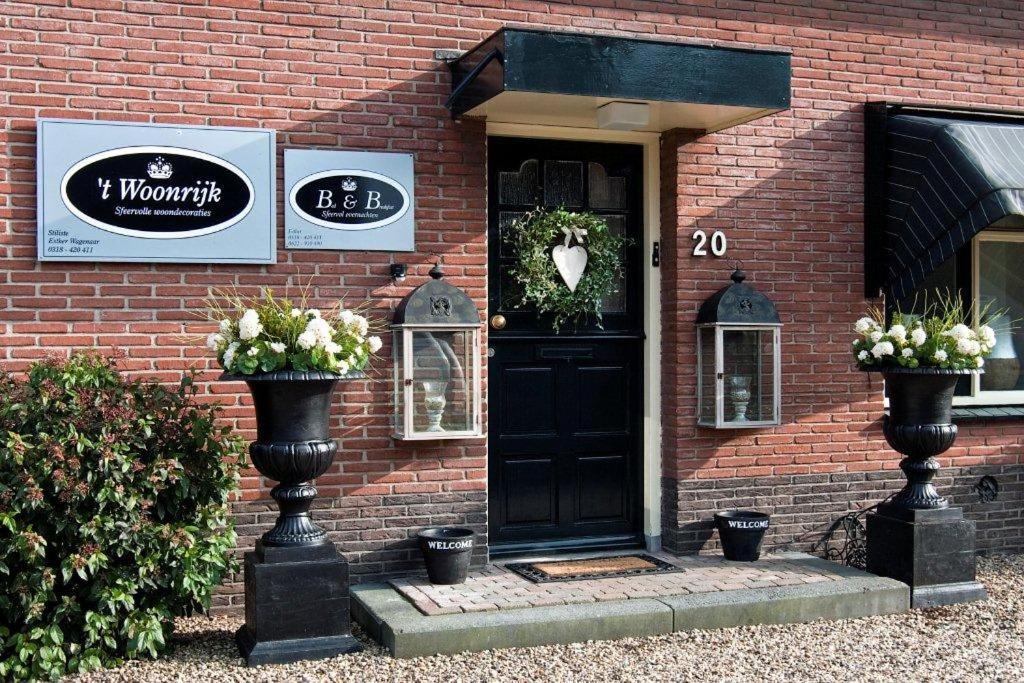 une porte noire sur un bâtiment en briques avec des fleurs sur lui dans l'établissement Het Woonrijk, à Bennekom
