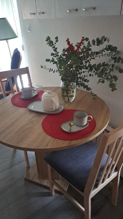 a wooden table with two plates and a vase with flowers at Srce Turopolja in Velika Gorica