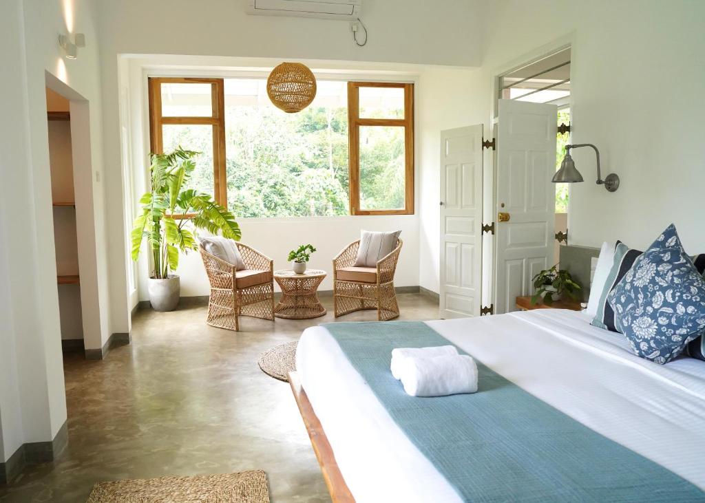 a bedroom with a large bed and a room with chairs at Shaka Villa in Dickwella