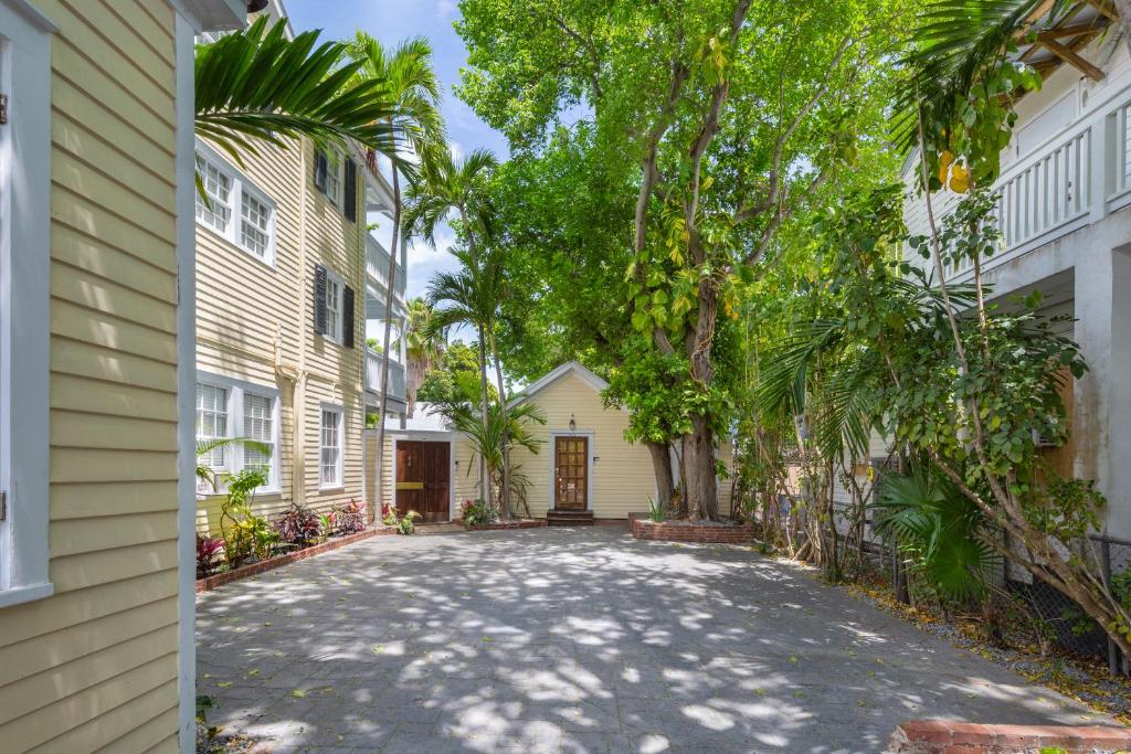 eine Auffahrt zwischen zwei Gebäuden mit Palmen in der Unterkunft Villa The Watson House in Key West