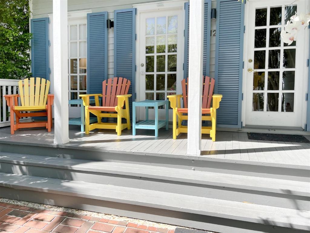 three chairs and a table on the front porch of a house at Parrotville in Key West