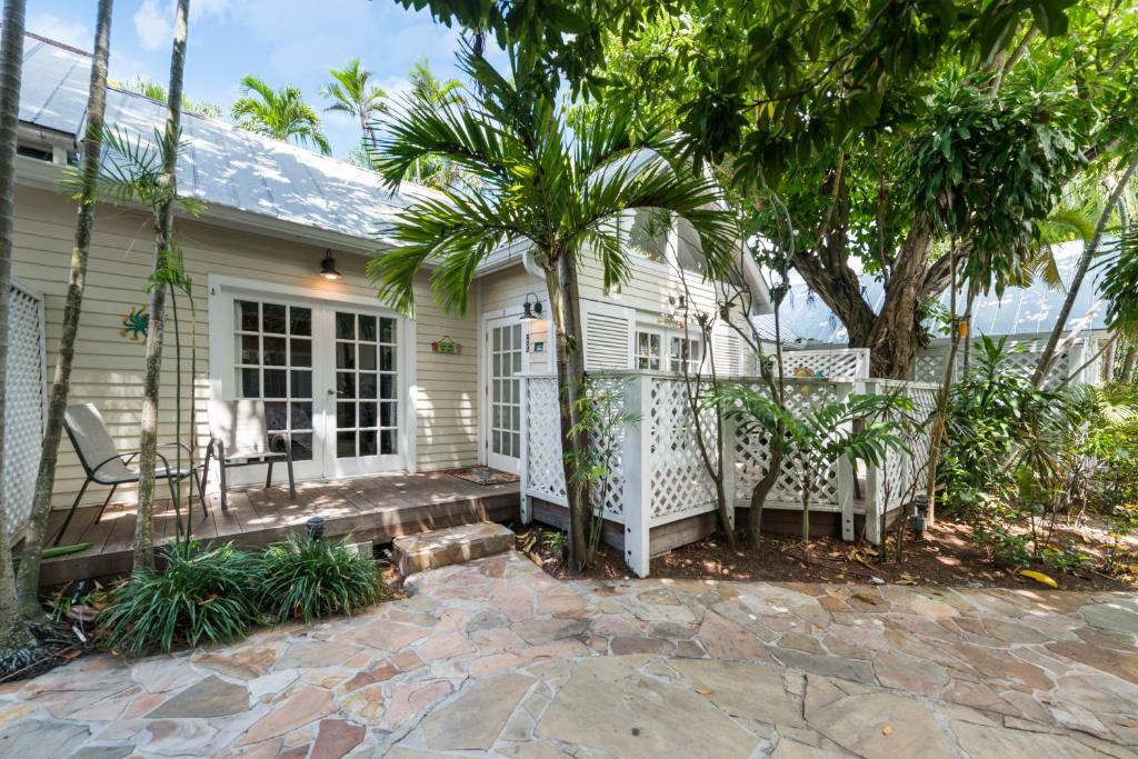 a white house with a palm tree and a patio at Sunset Suite Colony in Key West