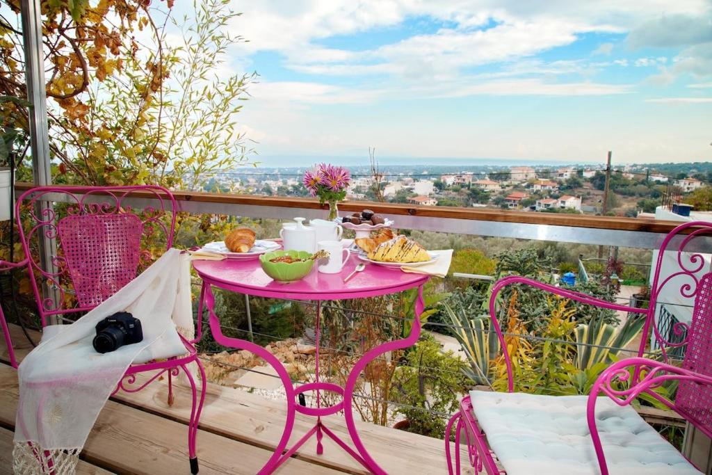 a pink table and chairs on a balcony with a view at Glass Home Nature meets Luxury in Nea Makri