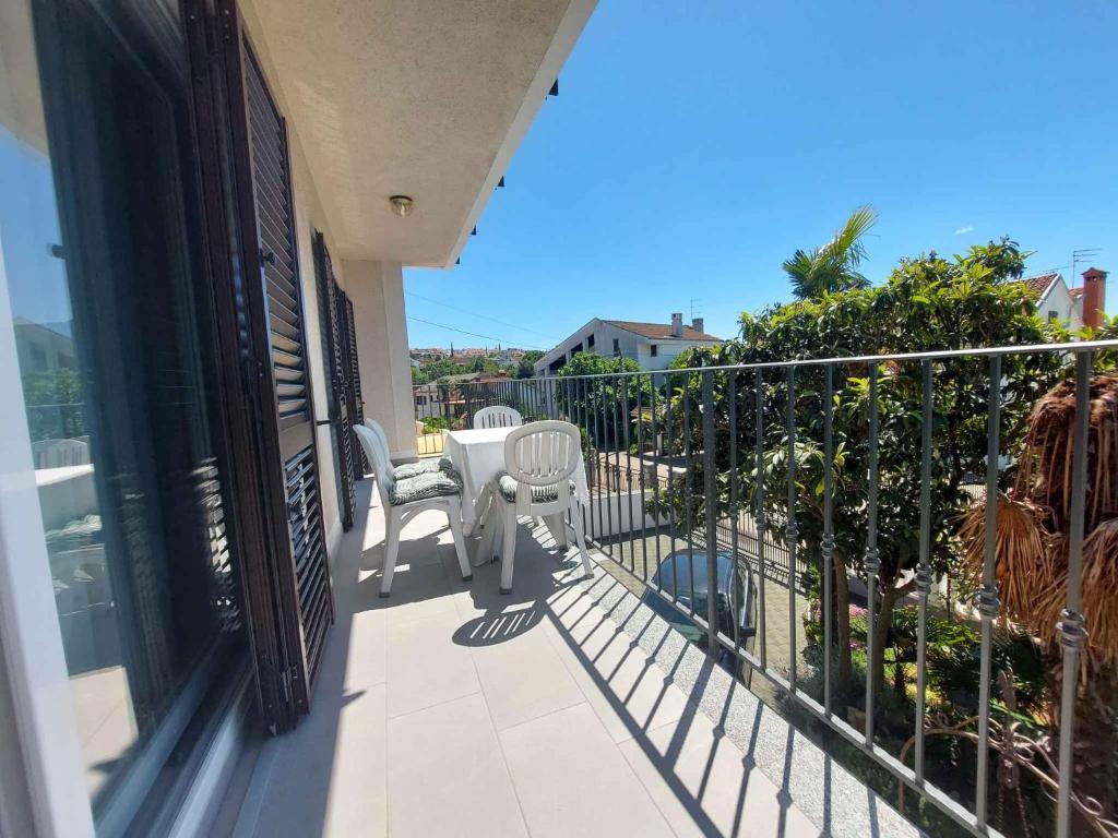 ein Balkon mit zwei weißen Stühlen und einem Zaun in der Unterkunft Apartment in Malinska 50 in Malinska