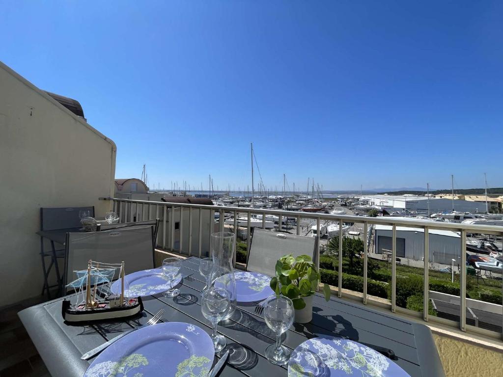 - une table avec des verres sur un balcon avec vue sur le port dans l'établissement Appartement 3 pièces - Gruissan GN160-434, à Gruissan