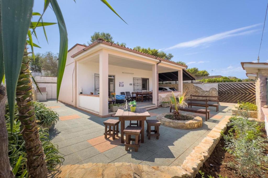 a patio with picnic tables and benches in front of a house at White Sand Private Villa Near The Sea, Wifi in Torre Squillace