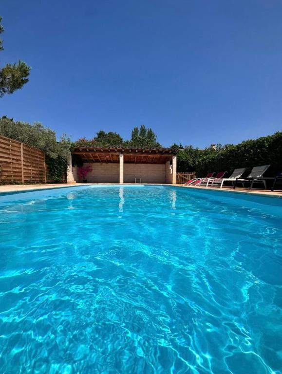 une piscine avec de l'eau bleue devant un immeuble dans l'établissement VILLA DE LA ROQUE, à Eygalières