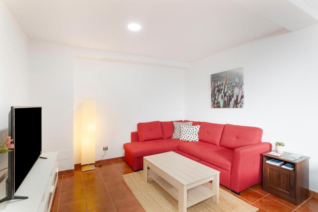 a living room with a red couch and a table at Casa Alejandro in Firgas