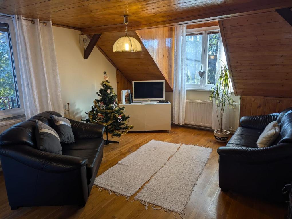 a living room with two leather couches and a christmas tree at Family Apartman by Budapest in Göd