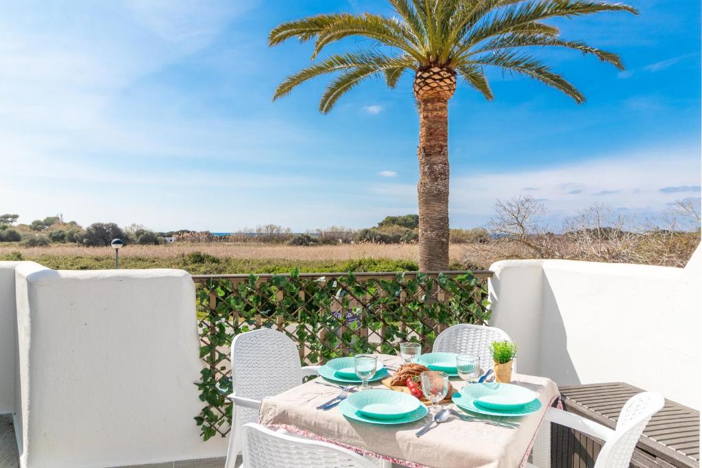 a table with chairs and a palm tree on a patio at Ca'n Pekos Apartamento en la playa de Son Bou in Son Bou