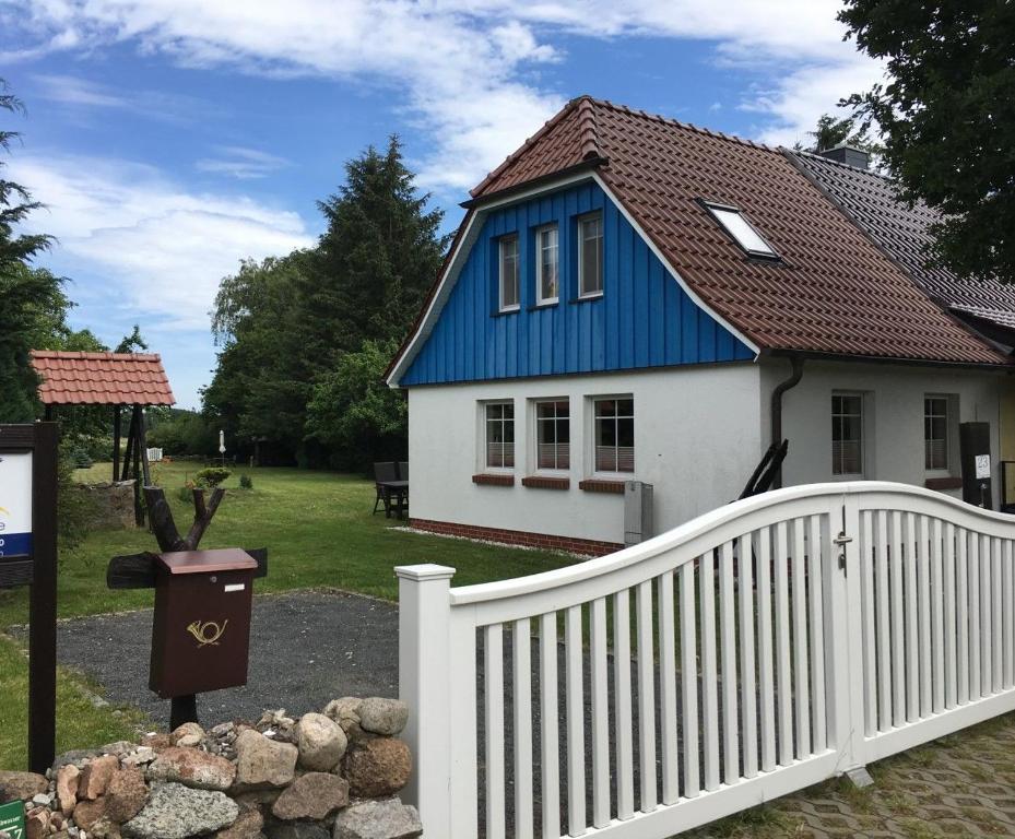 een blauw-wit huis met een wit hek bij Ferienhaus zur Kranichweide in Bodstedt