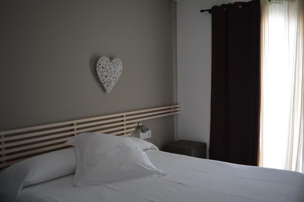 a bedroom with a white bed with a heart on the wall at Hotel Nou Estrelles in Cadaqués