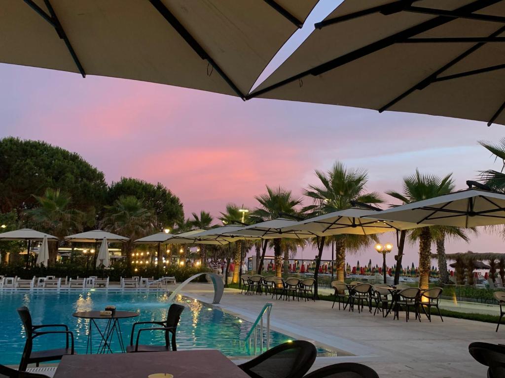 a resort with a pool with tables and umbrellas at Bounty Hotel in Golem
