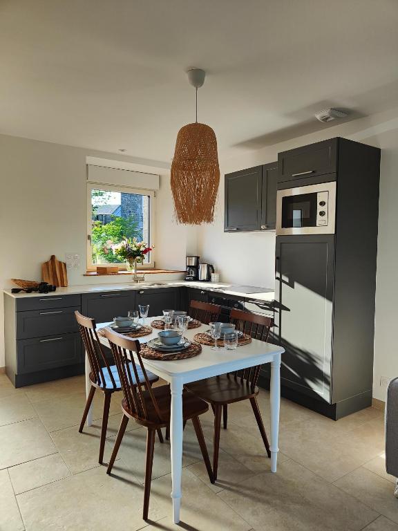 une cuisine avec une table blanche et des chaises et une cuisine avec des appareils noirs dans l'établissement Maison Louvel - proche du Mont-Saint-Michel, à Saint-Aubin-de-Terregatte