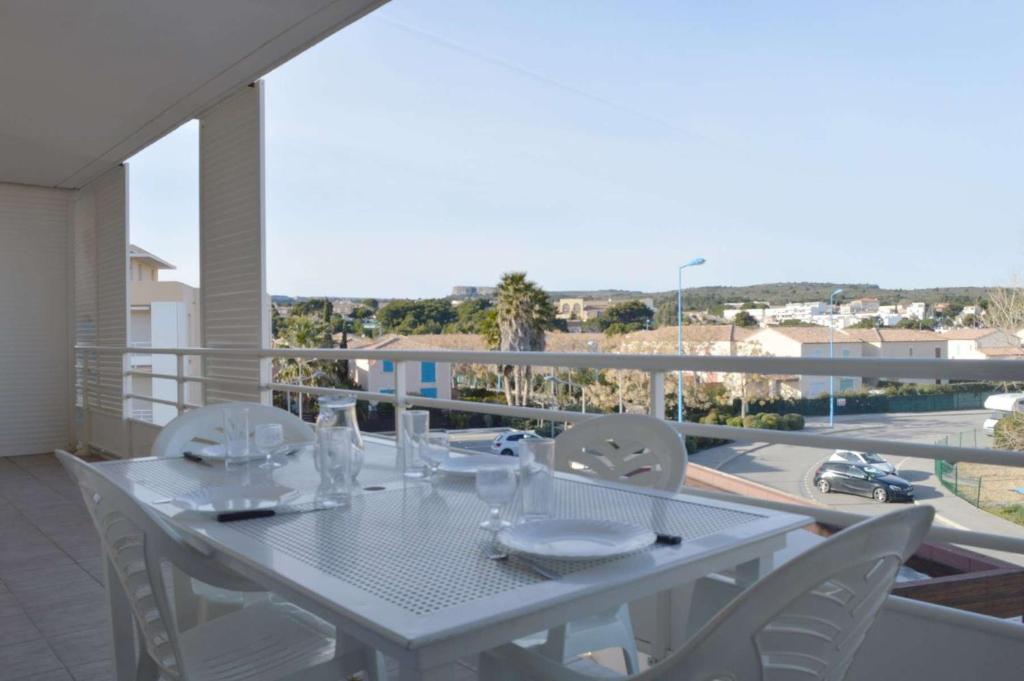 une table blanche et des chaises sur un balcon dans l'établissement NP610-B230 Appartement 3 pièces Narbonne Plage, à Narbonne-Plage