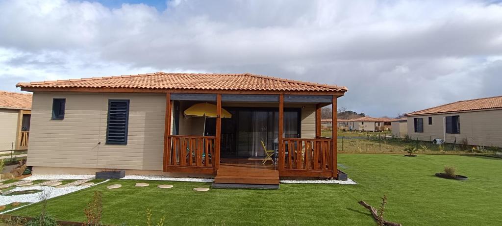 une petite maison avec une terrasse dans une cour dans l'établissement Charmant Cottage, à Saubrigues