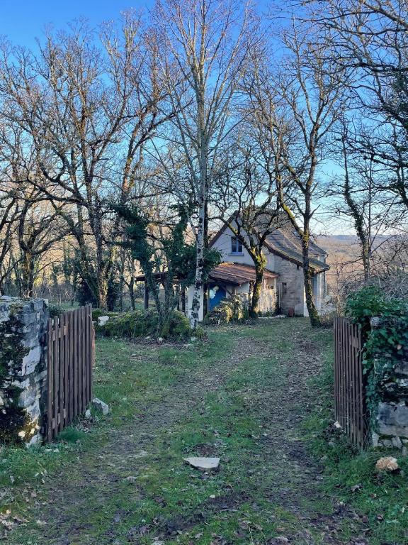 une clôture devant une maison arborée dans l'établissement Charming detached house in beautiful Calvignac, à Calvignac