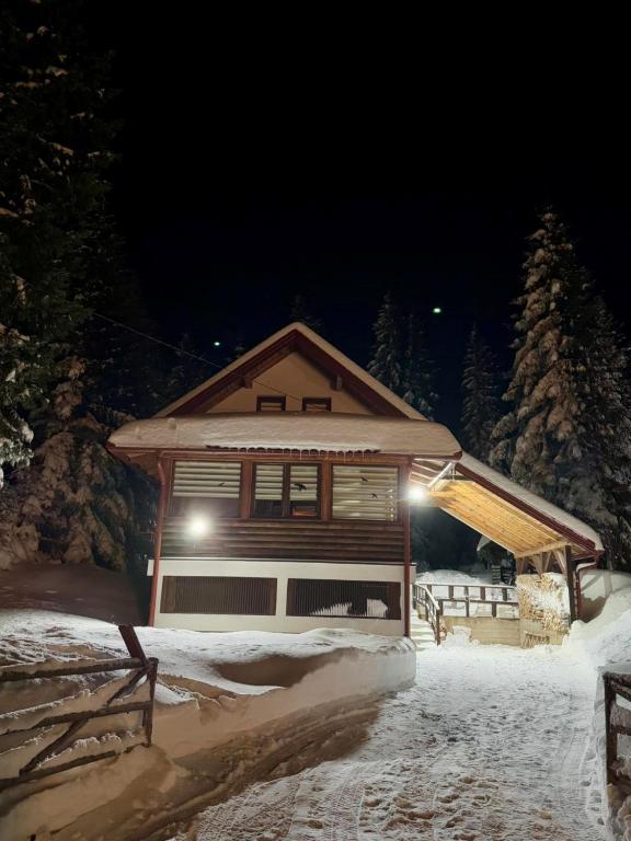una casa nella neve di notte con le luci di Winter cottage TT a Jahorina