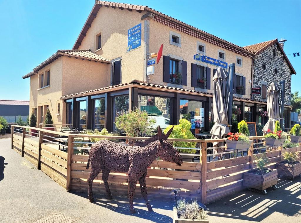 une statue d'un âne debout devant une clôture dans l'établissement Auberge du Couvige, à Le Bouchet-Saint-Nicolas