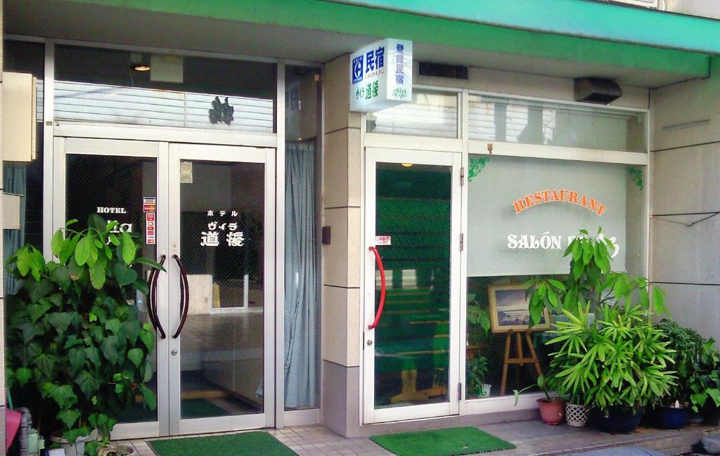 una tienda con puertas de cristal y plantas delante de ella en Hotel Villa Dogo, en Matsuyama