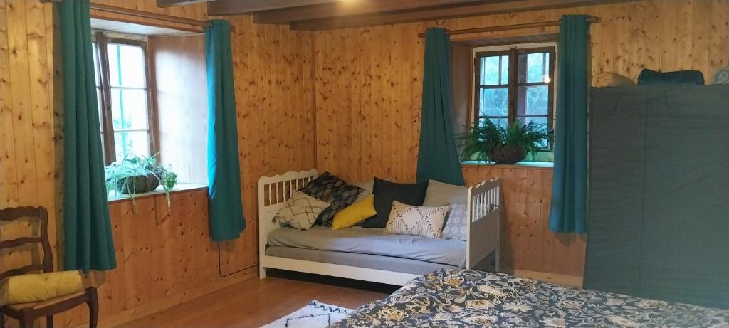 a bedroom with a couch in a room with two windows at L'Essentiel in Arbusigny