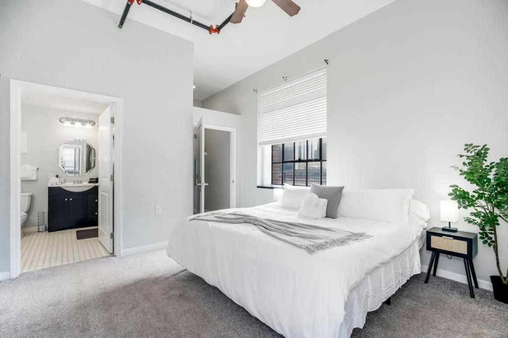 a white bedroom with a large bed and a bathroom at Chic 2BR-Parking, Rooftop,Near Arrowhd & TMobile in Kansas City
