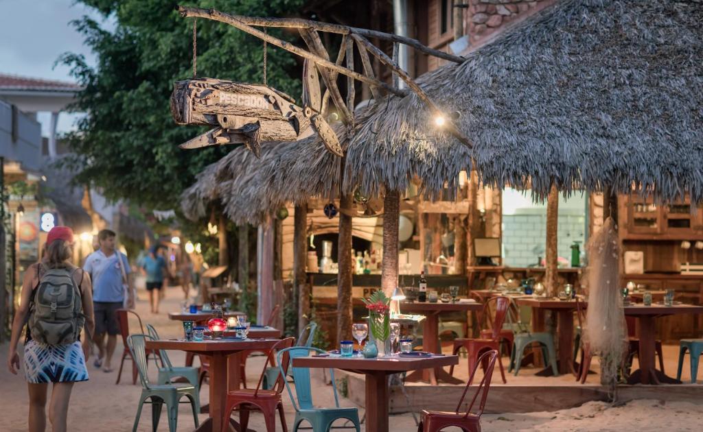 a group of tables and chairs with people walking down a street at Pescador - Pousada de Charme in Jericoacoara